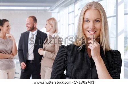 Portrait of happy businesswoman with team at office.