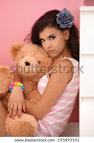 Attractive young girl hugging toy bear, looking at camera.