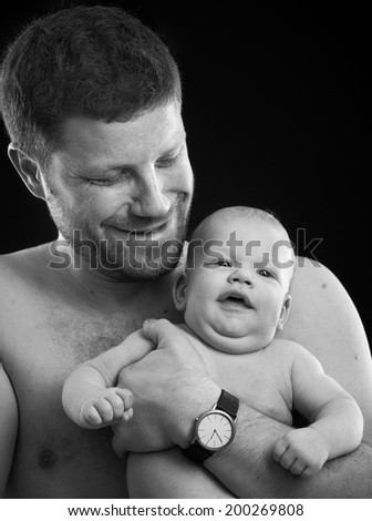 Black and white photo of father and newborn baby smiling happy.