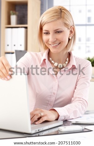 Happy blonde, smiling, casual caucasian businesswoman with laptop computer at business office. Close up.