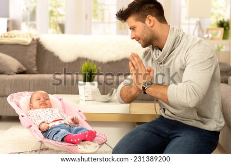 Desperate father kneeling by crying baby, praying for peace.