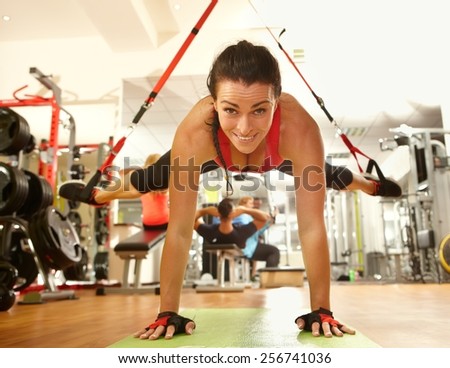 Happy woman enjoying hard suspension training in gym.