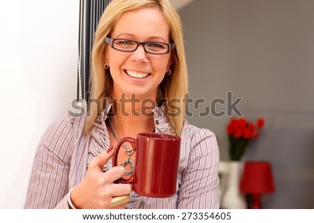 Closeup portrait of happy blonde woman holding tea mug, smiling, looking at camera.