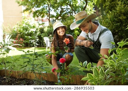 Young couple gardening outside, smiling happy.