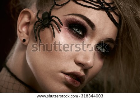 Closeup portrait of woman in halloween makeup, having spider on her face.