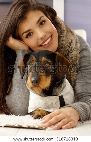 Closeup portrait of beautiful young woman hugging dog, smiling happy, looking at camera.