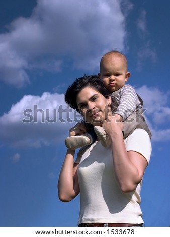 A one year old baby and his mom are spending some time together outdoor. The background is the clear blue sky.