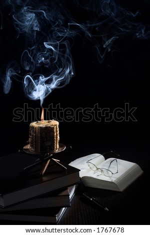 Still-life on a desk: an old candle, books and glasses