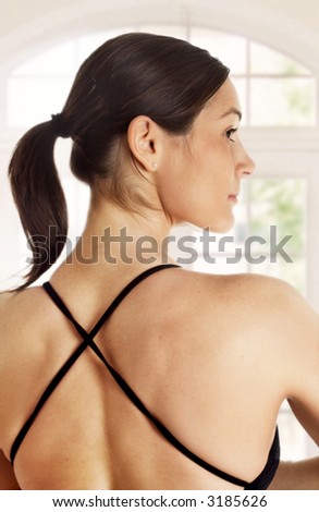 Young woman with beautifully muscular back is sitting in a yoga pose.