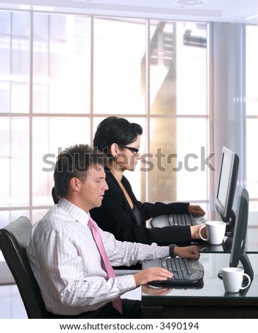 Young office workers are sitting in front of their computer screens. Daylight, indoor, office.