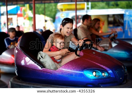 Mother and 2 years old baby pay drive dodgem together in the theme-park.