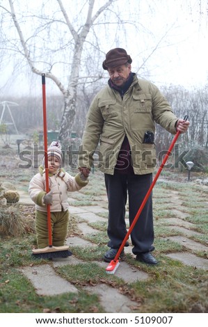 Grandpa and grandson spend time together outdoor in the garden on a cold winter day.