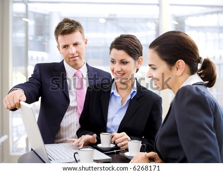 Young business people working over a laptop computer and drinking coffee.