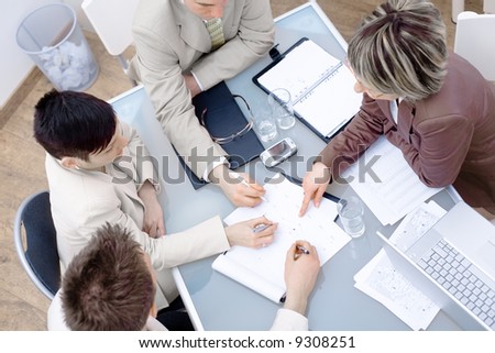 High-angle view of businesspeople having a meeting at office, sitting around the desk and talking.
