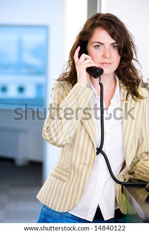 Young female receptionist receiving phone calls at office reception.
