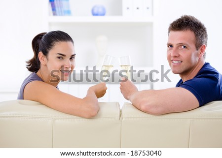 Love couple drinking champagne at home on sofa.