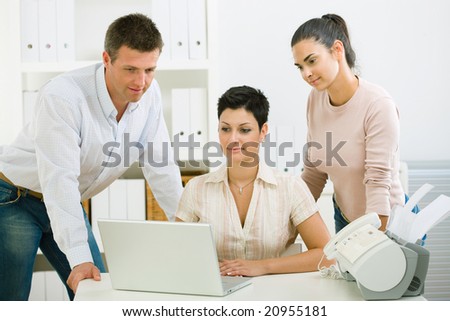 Team of happy office people working on laptop computer.