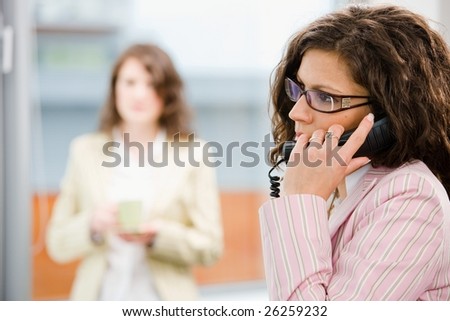 Businesswomen at office, receptionist calling on phone.