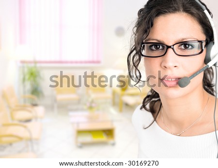 Young female receptionist at clinic reception talking on headset.