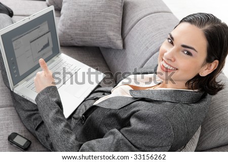 Young businesswoman sitting on sofa, working with laptop computer. Isolated on white background, overhead view.