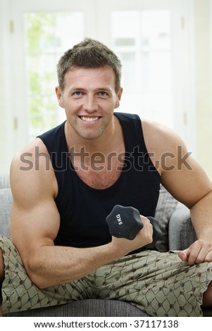 Muscular Man Sitting At Home On Sofa, Doing Excercise With Hand Barbell ...