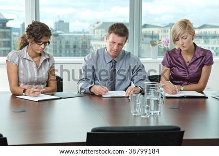 Panel of business people sitting at table in meeting room conducting job interview.