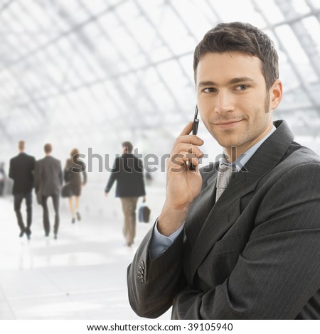 Closeup portrait of happy businessman talking on mobile in front of office building windows.