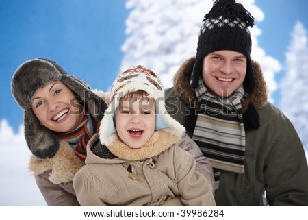 Portrait of happy family together outdoor in snow on a cold winter day, laughing, smiling.