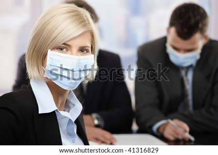 Businesswoman fearing h1n1 swine flu virus wearing protective face mask during meeting at office.