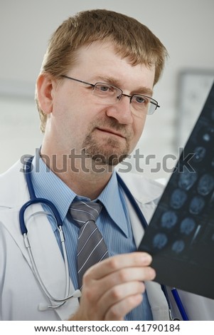 Medical office - portrait of middle-aged male doctor looking at computer tomograph scan.