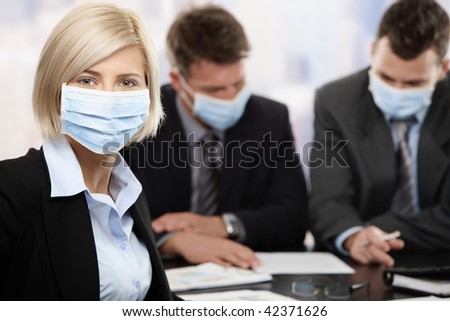 Businesswoman fearing h1n1 swine flu virus wearing protective face mask during meeting at office.