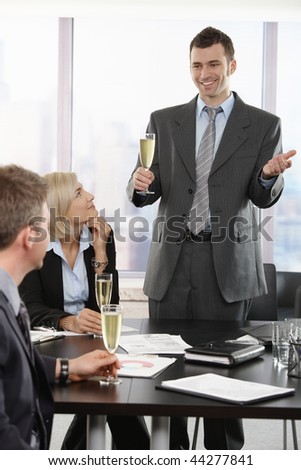 Businessman raising toast with champagne flutes, smiling.