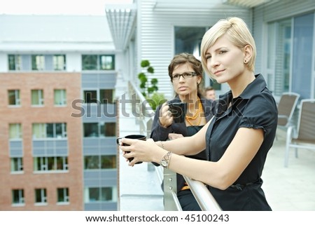 Businesswomen having break on office terrace outdoor drinking coffee.