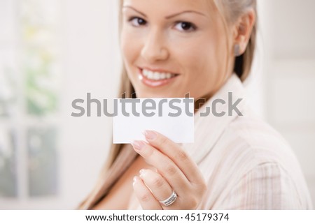 Beautiful young woman showink a blank white business card with copy space. Selective focus on card.