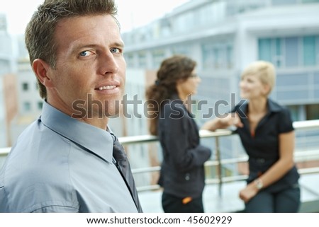 Business people talking on terrace outdoor of office building. Businessman in front.