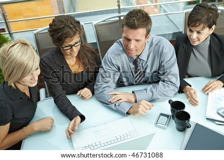 Group of young business people sitting around table on office terrace outdoor, talking and working together. Overhead view.