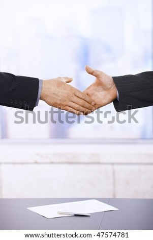 Businessmen shaking hands in office. Close-up of hands.