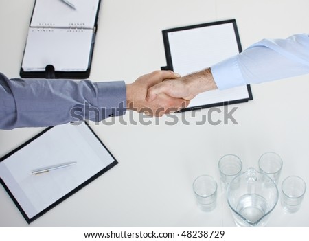 Closeup of hands, businessmen shaking hand over meeting table in office.