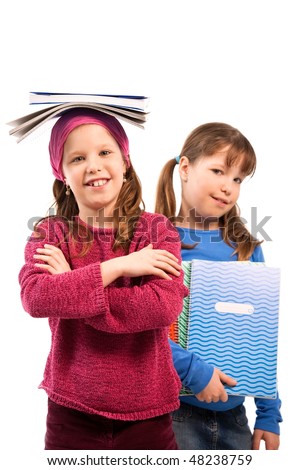 Schoolgirls posing with exercise books, girl balancing books on top of head, other holding in arm.
