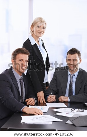 Portrait of smiling businesspeople at meeting table in office.