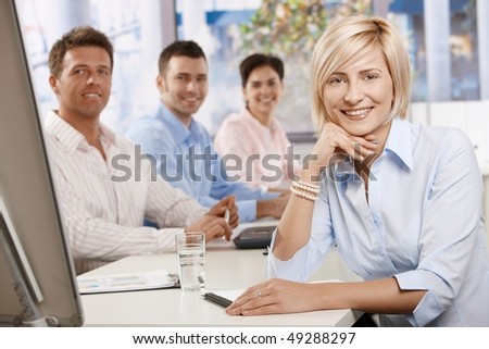 Happy businesswoman on business meeting at office, leaning on table, looking at camera and smiling.