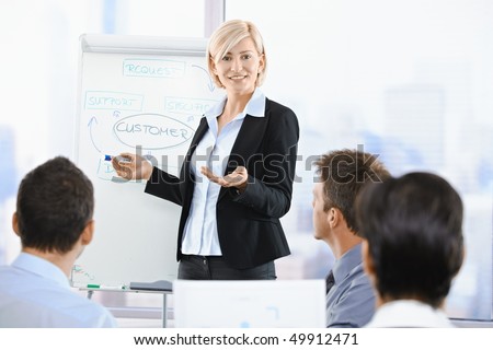 Business people sitting on presentation at office. Businesswoman presenting on whiteboard.