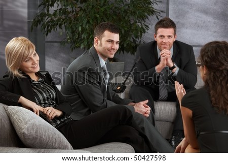 Corporate businesspeople having break, resting on sofa, talking.