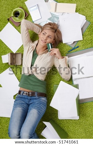 Happy woman lying on floor holding credit card, bills all around.