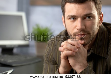 Determined office worker sitting at desk, thinking.