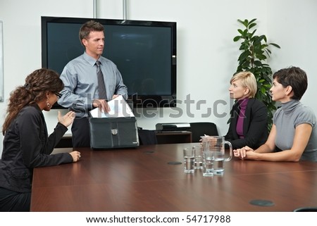 Business people sitting around meeting table in board room.