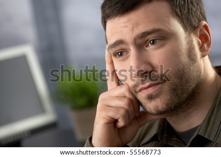 Troubled office worker thinking hard in office.