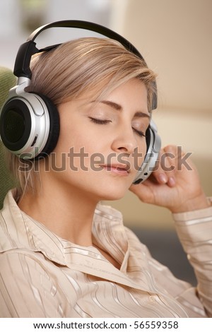Portrait of smiling woman sitting with eyes closed listening to music on headset.