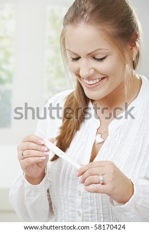 Portrait of a happy young woman holding positive pregnancy test.