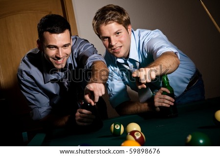 Two young men discussing snooker game, having beer, pointing at table.?